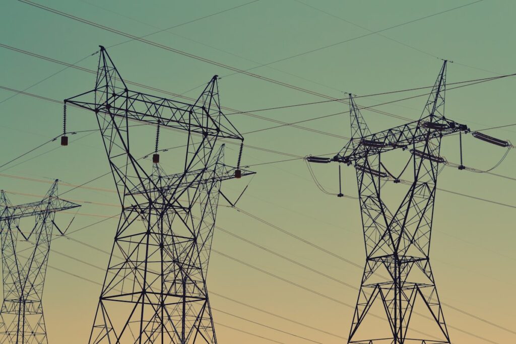Højspændingsmaster i energinettet ved solnedgang